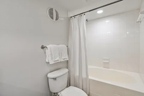 a white toilet sitting next to a bath tub
