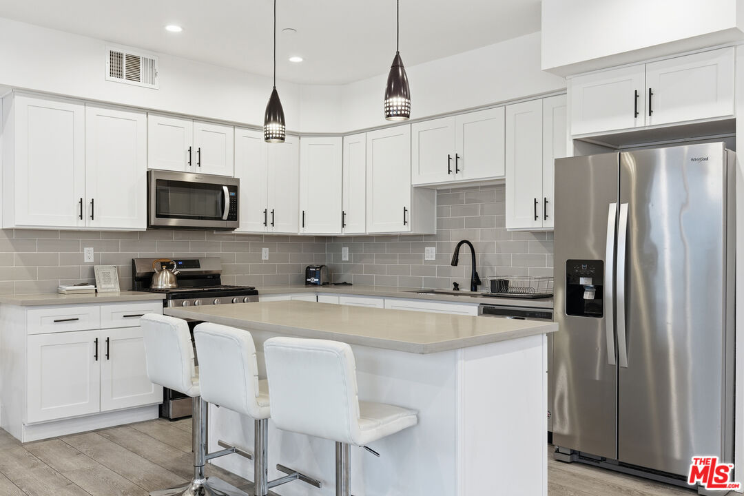 13822 Oxnard Street Van Nuys, CA 91401 - Photo 4 of 23 a kitchen with stainless steel appliances granite countertop a stove a sink dishwasher a refrigerator and a microwave oven with wooden cabinets