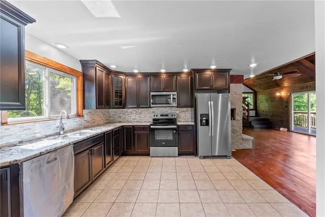 a large kitchen with stainless steel appliances granite countertop a large stove a sink dishwasher and a refrigerator with wooden cabinets