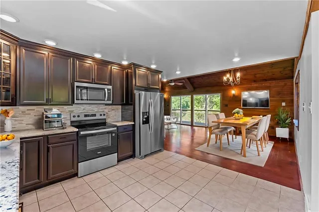 a kitchen with stainless steel appliances granite countertop a stove top oven a sink dishwasher a dining table and chairs with wooden floor