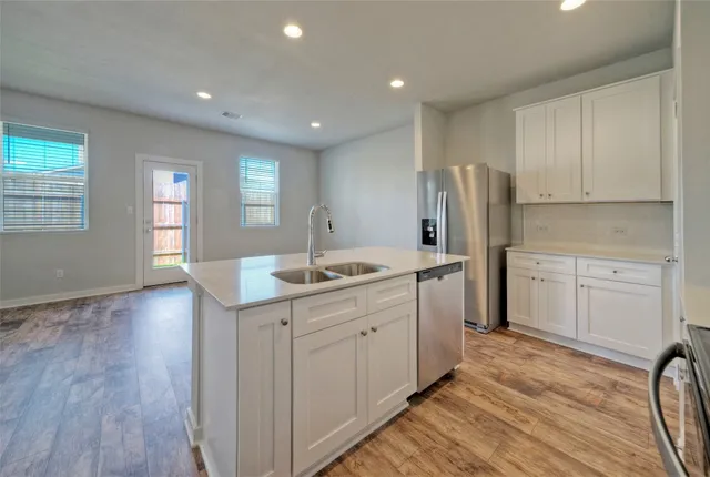 a kitchen with stainless steel appliances granite countertop a sink stove refrigerator and cabinets