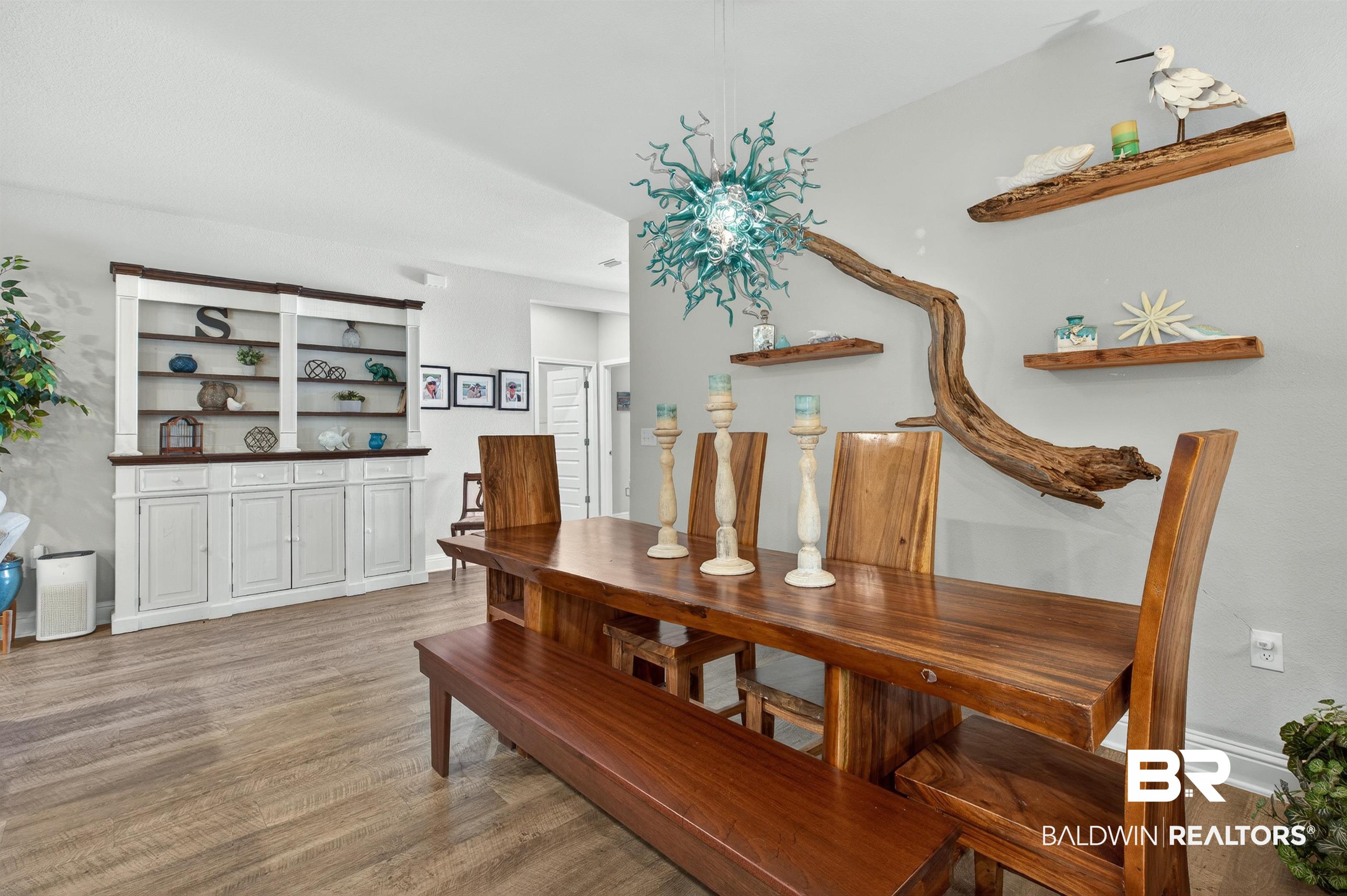 8735 Bronze Lane Foley, AL 36535 - Photo 19 of 58 Spacious dining area featuring wood-finish flooring, a built-in display cabinet with open shelving and lower storage, and a unique light fixture