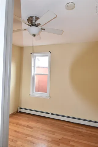 an empty room with wooden floor chandelier fan and windows