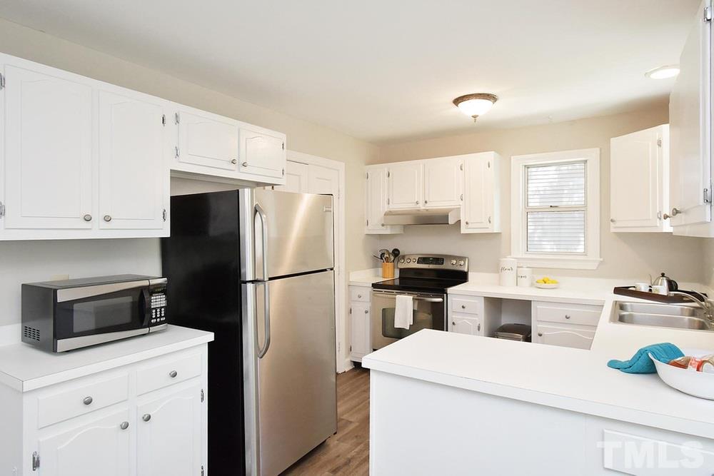 5903 Sentinel Drive Raleigh, NC 27609 - Photo 7 of 26 White cabinets in the eat in kitchen with stainless and black appliances.