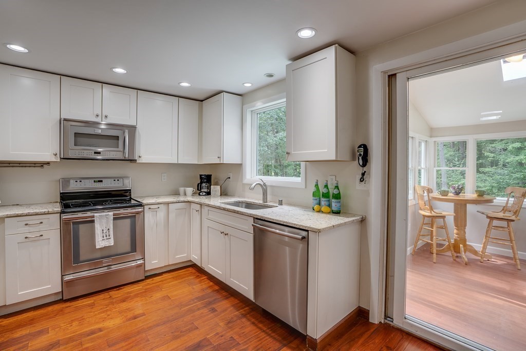 40 Tenney Road Rowley, MA 01969 - Photo 9 of 28 a kitchen with stainless steel appliances granite countertop a stove a sink a refrigerator and white cabinets with wooden floor