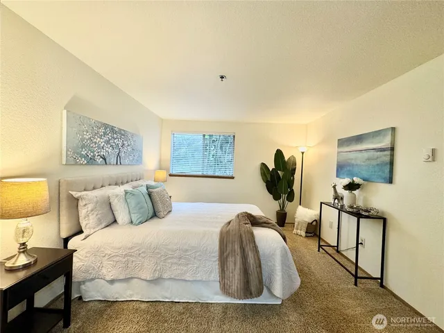 a bedroom with a bed a mirror and lamp on dresser