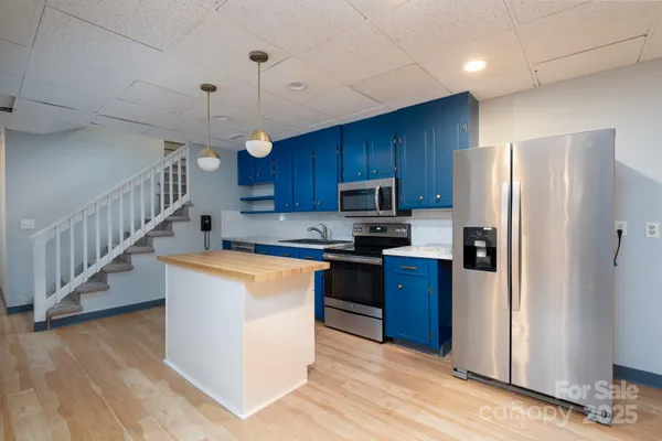 a kitchen with stainless steel appliances granite countertop a refrigerator a stove top oven a sink and a center island