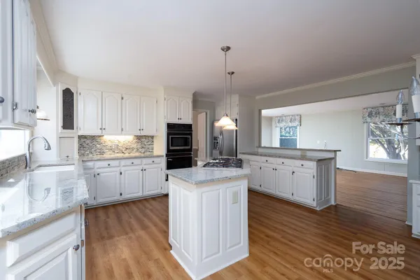 a kitchen with cabinets appliances wooden floor and a window