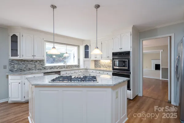 a kitchen with stainless steel appliances granite countertop a stove a refrigerator and a sink with wooden floor