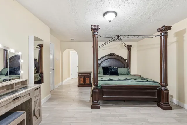 a bedroom with a bed table and flat screen tv