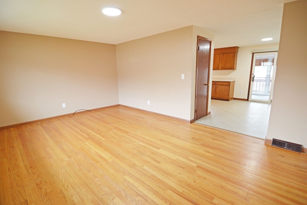 122 Garnet Street Springfield, MA 01129 - Photo 4 of 36 a view of an empty room with wooden floor and a kitchen