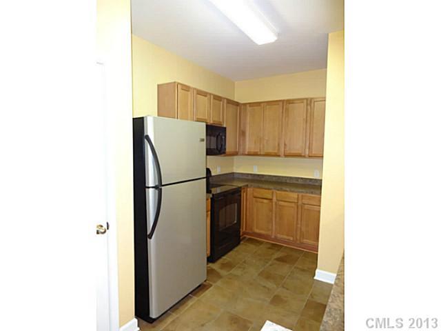 10125 Westmoreland Road, Unit IB Cornelius, NC 28031 - Photo 7 of 16 a kitchen with a refrigerator sink and cabinets