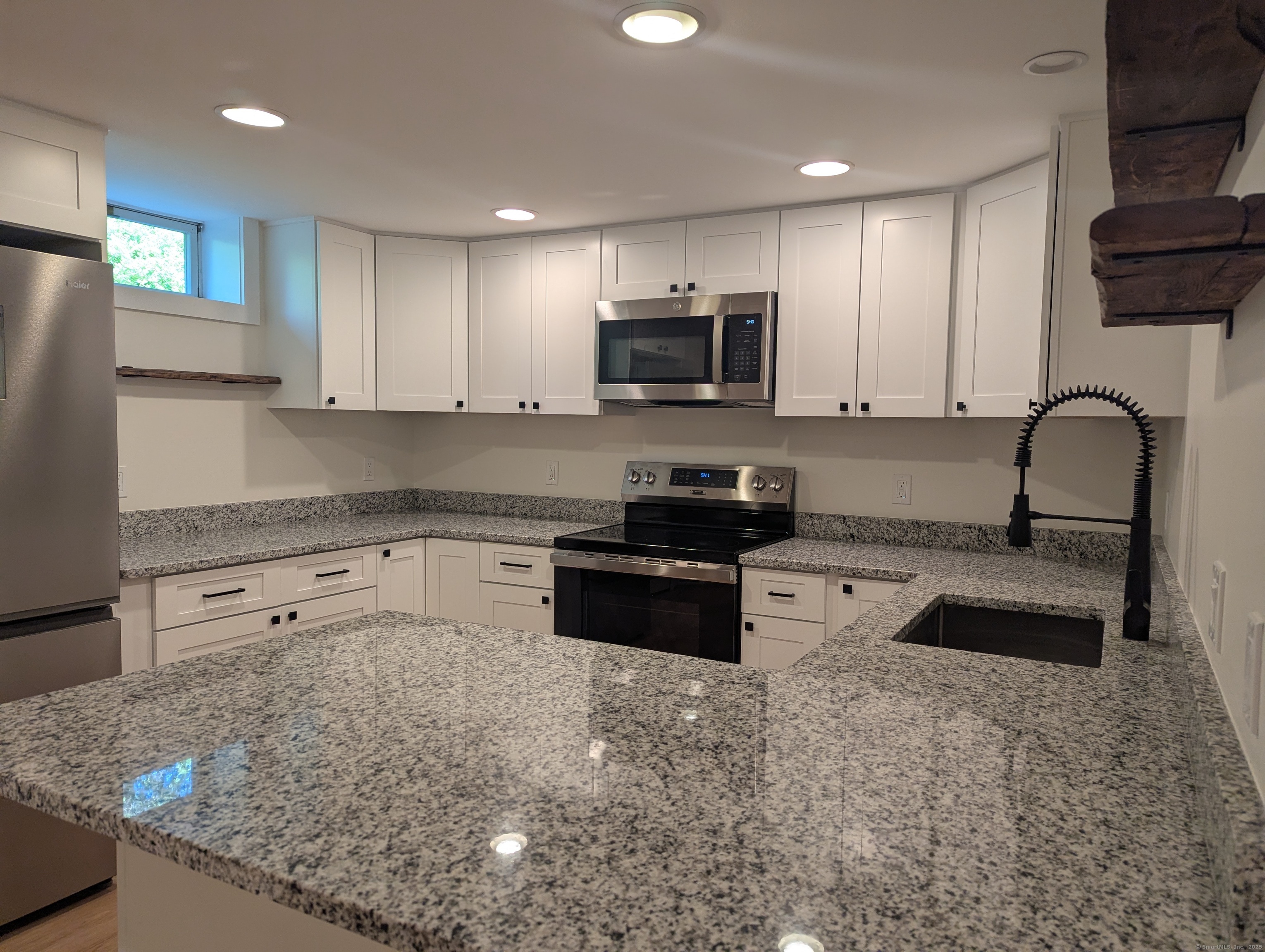 a kitchen with granite countertop a sink a counter top space appliances and cabinets
