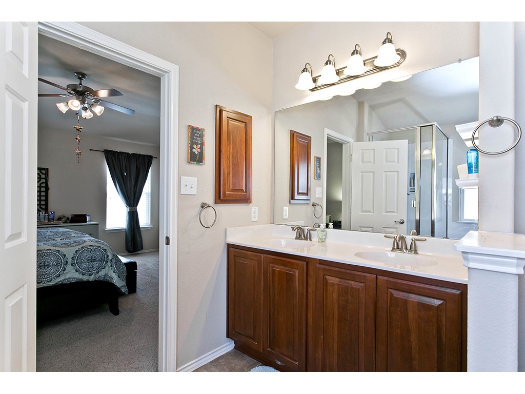 1808 Sand Creek Road Cedar Park, TX 78613 - Photo 16 of 25 Bathroom featuring a dual-sink vanity with a light-colored countertop and wood-finish cabinetry