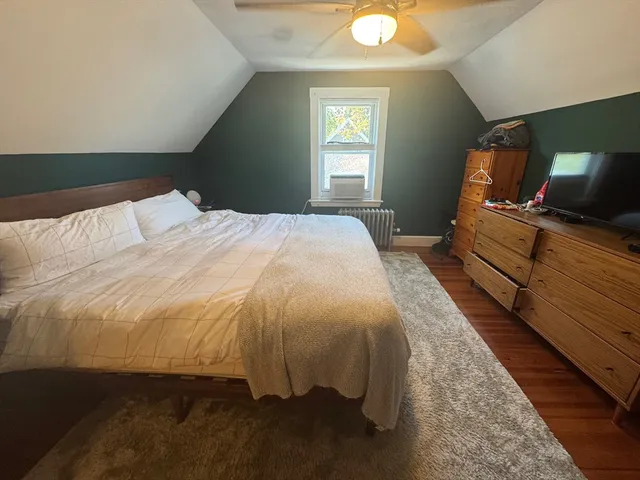a spacious bedroom with a bed and wooden floor