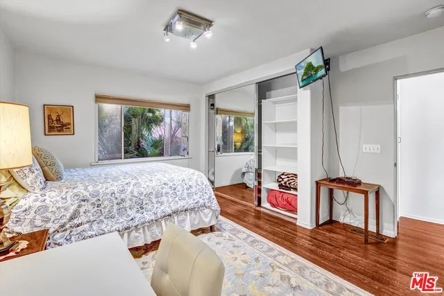 a bedroom with a bed and dresser with wooden floor