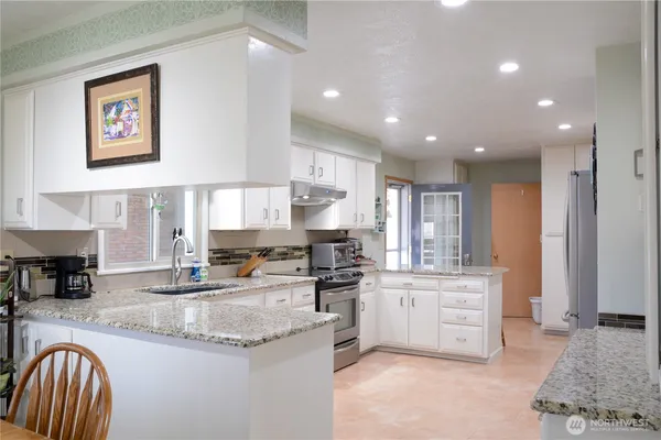 a kitchen with stainless steel appliances granite countertop a stove a sink and a refrigerator