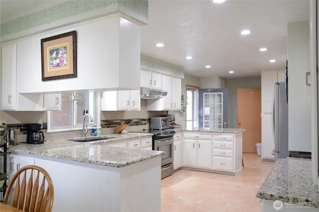 a kitchen with stainless steel appliances granite countertop a stove a sink and a refrigerator