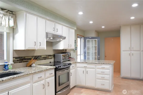 a kitchen with granite countertop white cabinets and white appliances