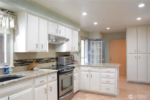 a kitchen with granite countertop white cabinets and white appliances