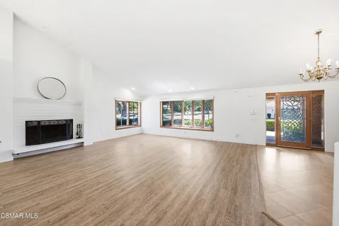 an empty room with windows and fireplace