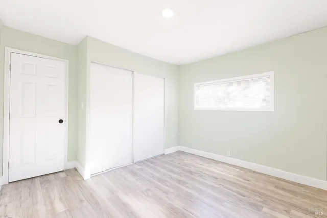 a view of a hallway with wooden floor and closet