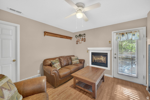1464 990 West Provo, UT 84601 - Photo 26 of 41 Living area featuring wood-finish flooring, a white-mantled fireplace, and a ceiling fan with integrated lighting