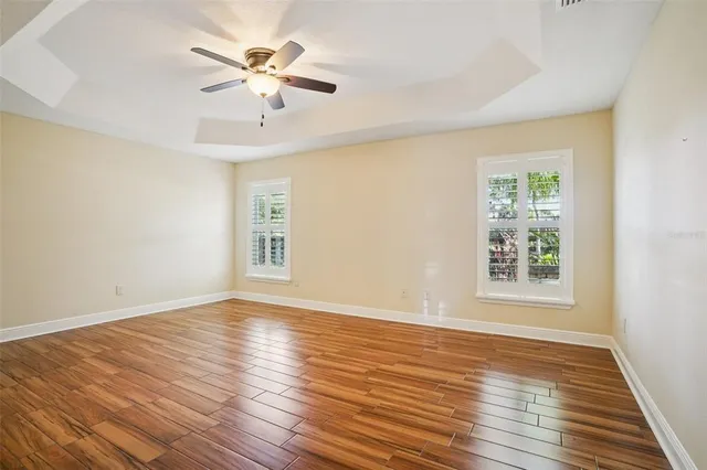 an empty room with wooden floor and a ceiling fan