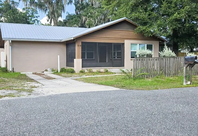 a view of a house with a yard and large tree