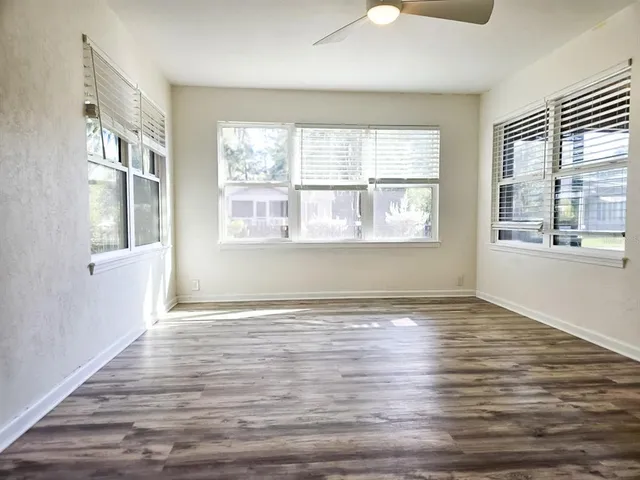 a view of an empty room with wooden floor and a window