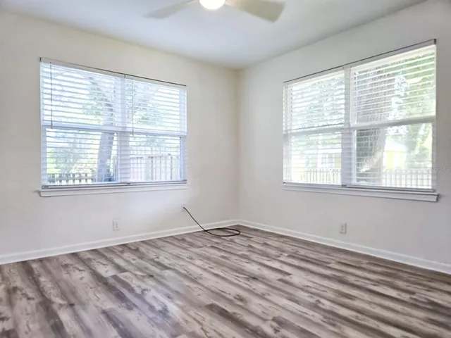 an empty room with wooden floor and windows