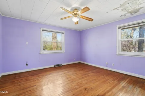 a view of an empty room with a window and wooden floor