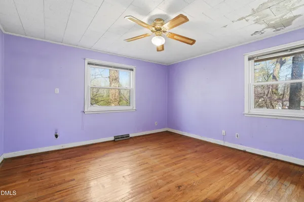 a view of an empty room with a window and wooden floor