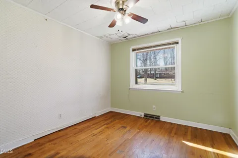 a view of empty room with wooden floor and fan