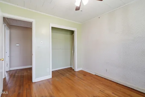 an empty room with wooden floor chandelier fan and windows