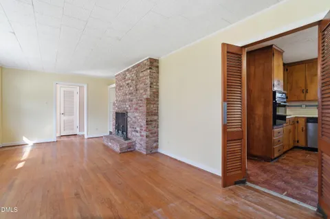 a view of empty room with wooden floor and fireplace