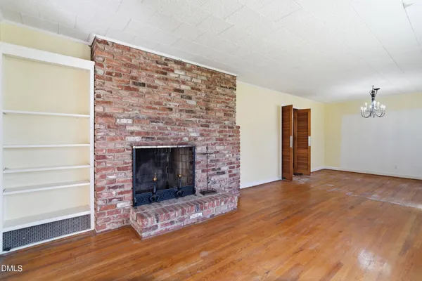 a view of an empty room with wooden floor fireplace and a window