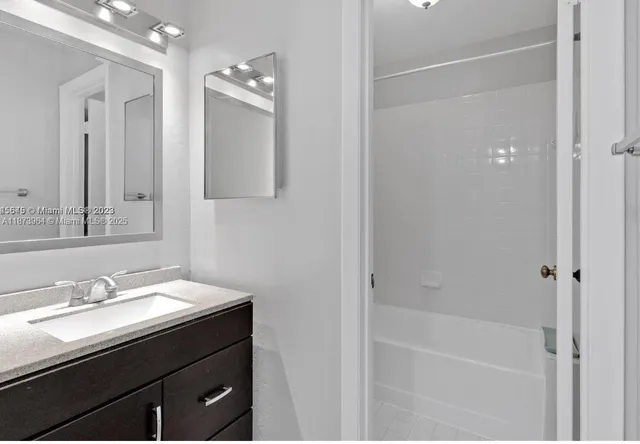 a bathroom with a bathtub sink vanity and mirror