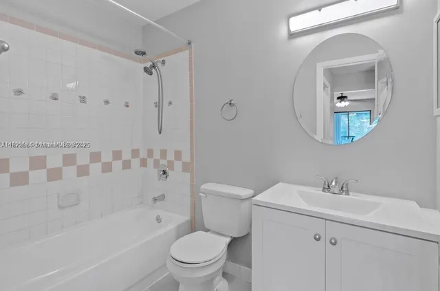 a bathroom with a toilet a sink a mirror a bathtub and vanity