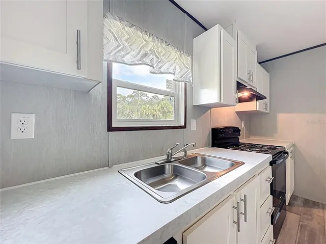 a kitchen with granite countertop cabinets stainless steel appliances and wooden floor