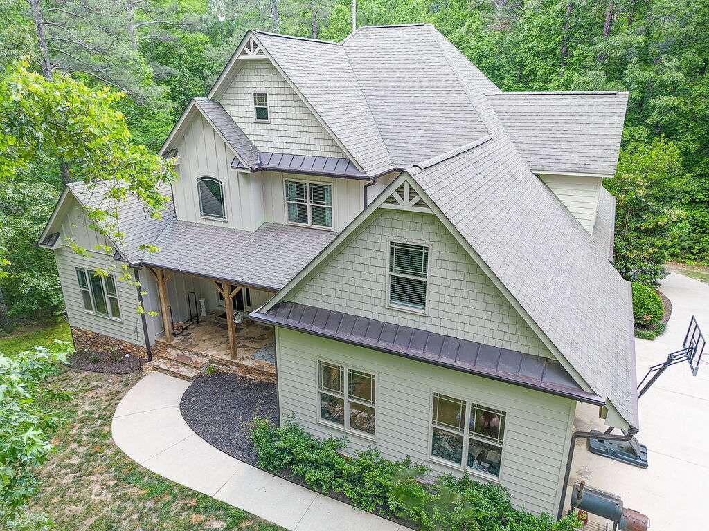 a aerial view of a house with yard and trees in the background