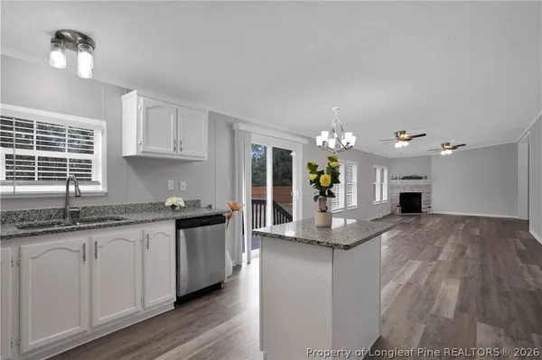 a kitchen with stainless steel appliances granite countertop a refrigerator a sink dishwasher a stove and white cabinets with wooden floor