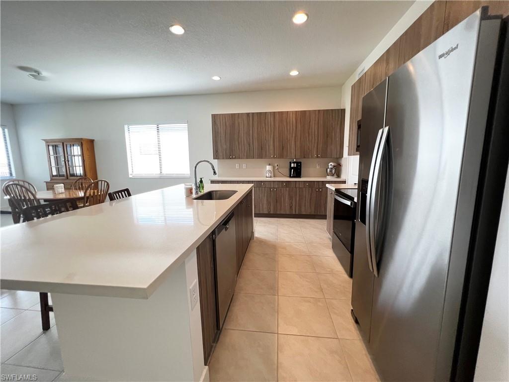 a kitchen with kitchen island a counter top space a sink a refrigerator a window and a counter top space