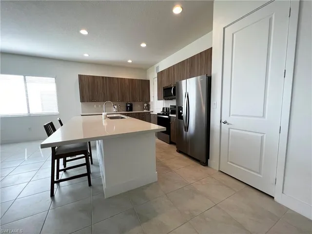 a kitchen with kitchen island a counter top space a sink a refrigerator a window and a counter top space