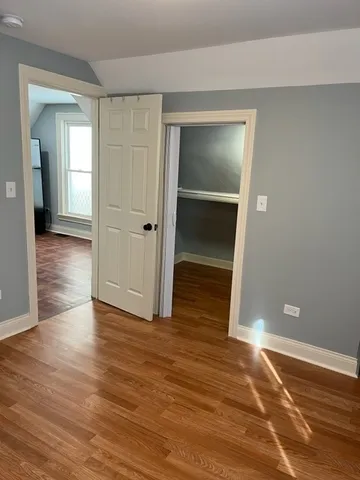 an empty room with wooden floor & closet area