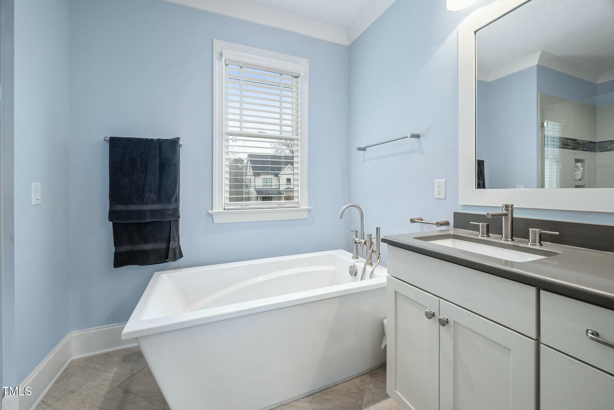 519 Peebles Street Raleigh, NC 27608 - Photo 20 of 43 a bathroom with a tub sink a window and mirror