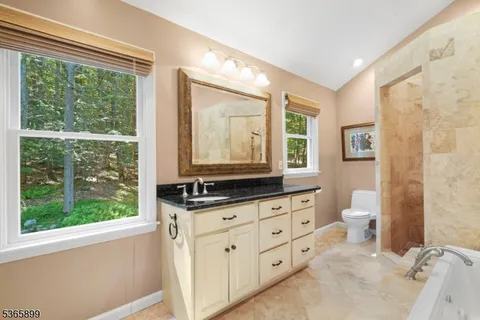 a bathroom with a granite countertop sink a toilet a mirror and a window