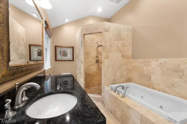a bathroom with a granite countertop tub a sink and a mirror