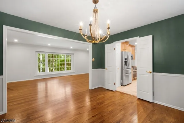 a view of a room with wooden floor chandelier and a window