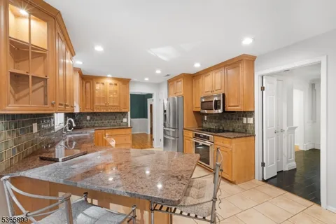 a kitchen with stainless steel appliances granite countertop a stove a sink a microwave a refrigerator and cabinets